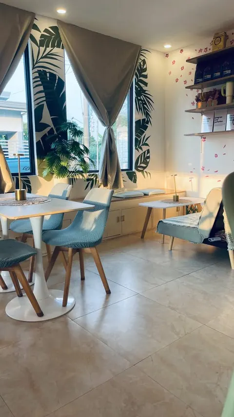 A window nook with a cushioned bench, a small table and a sofa in the sun