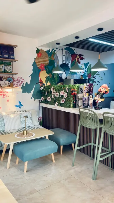 A sofa and ottomans in front of the counter, its painted mural and a photo garland