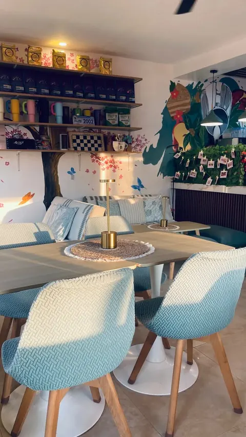 Textured aqua chairs around a wood table with a gold lamp, sofas behind
