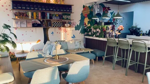 The lounge with sofas, wood tables and gold lamps beside the counter and its green bar stools