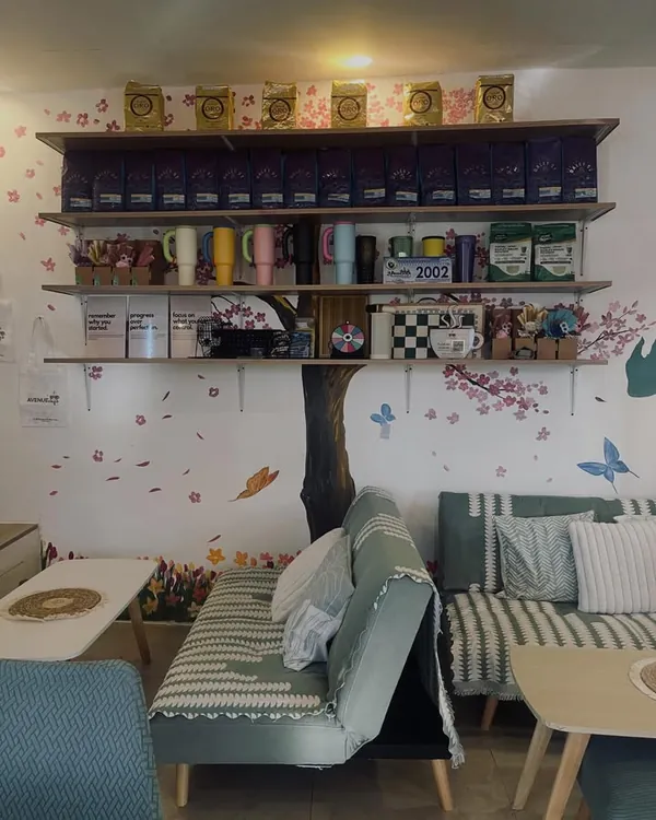 Sofas under a painted cherry blossom tree, with shelves of coffee bags and tumblers